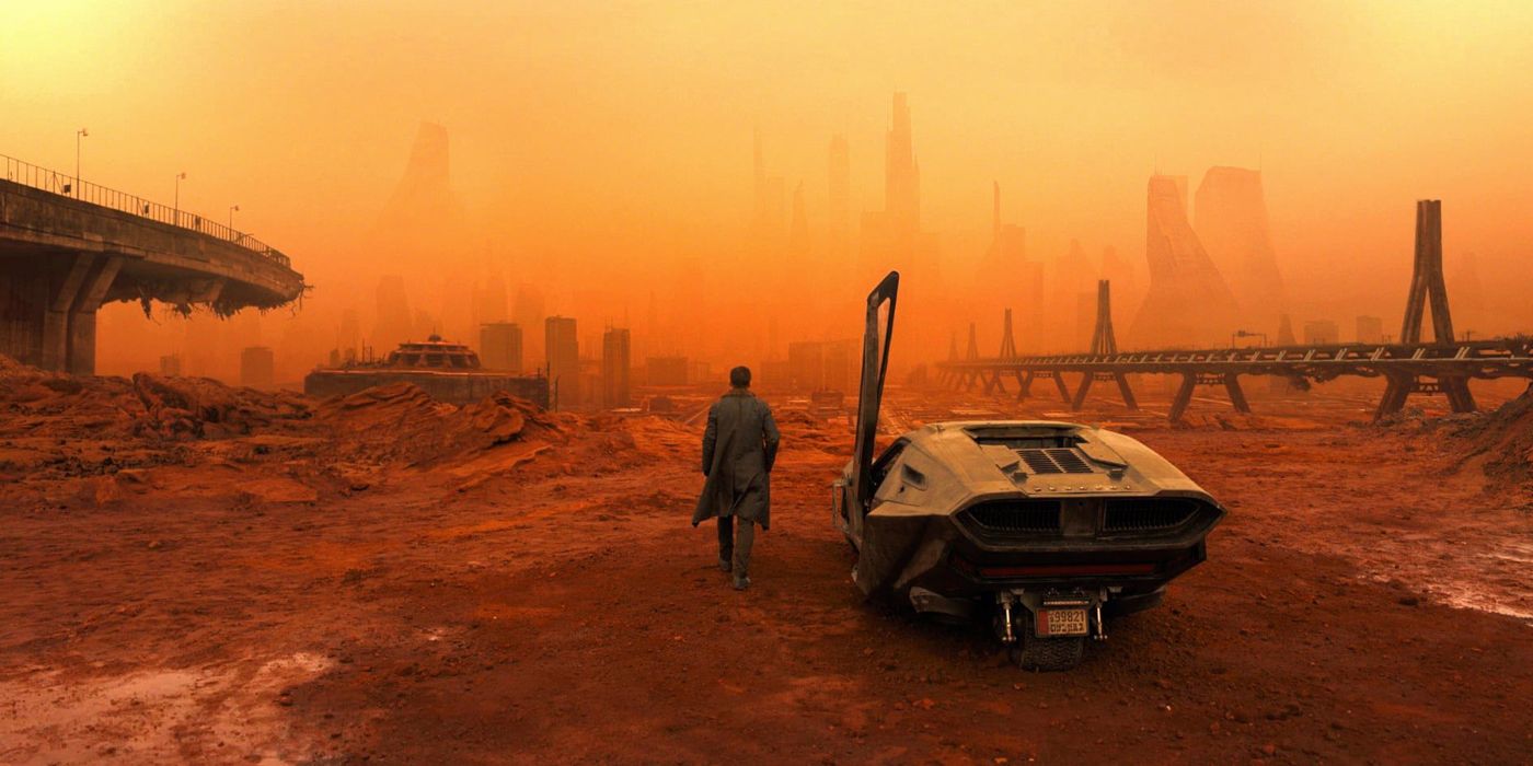 K walking away from his car towards the orange haze of the the Las Vegas skyline in Blade Runner 2049