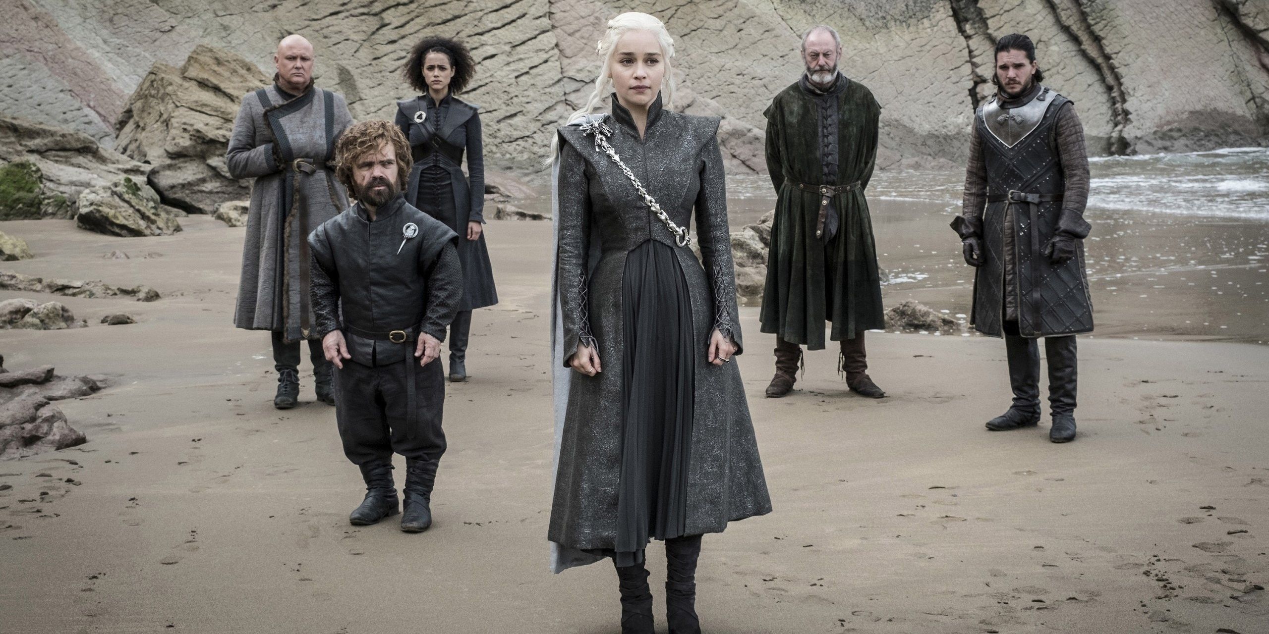Daenerys with her counsel standing behind her on a beach. 