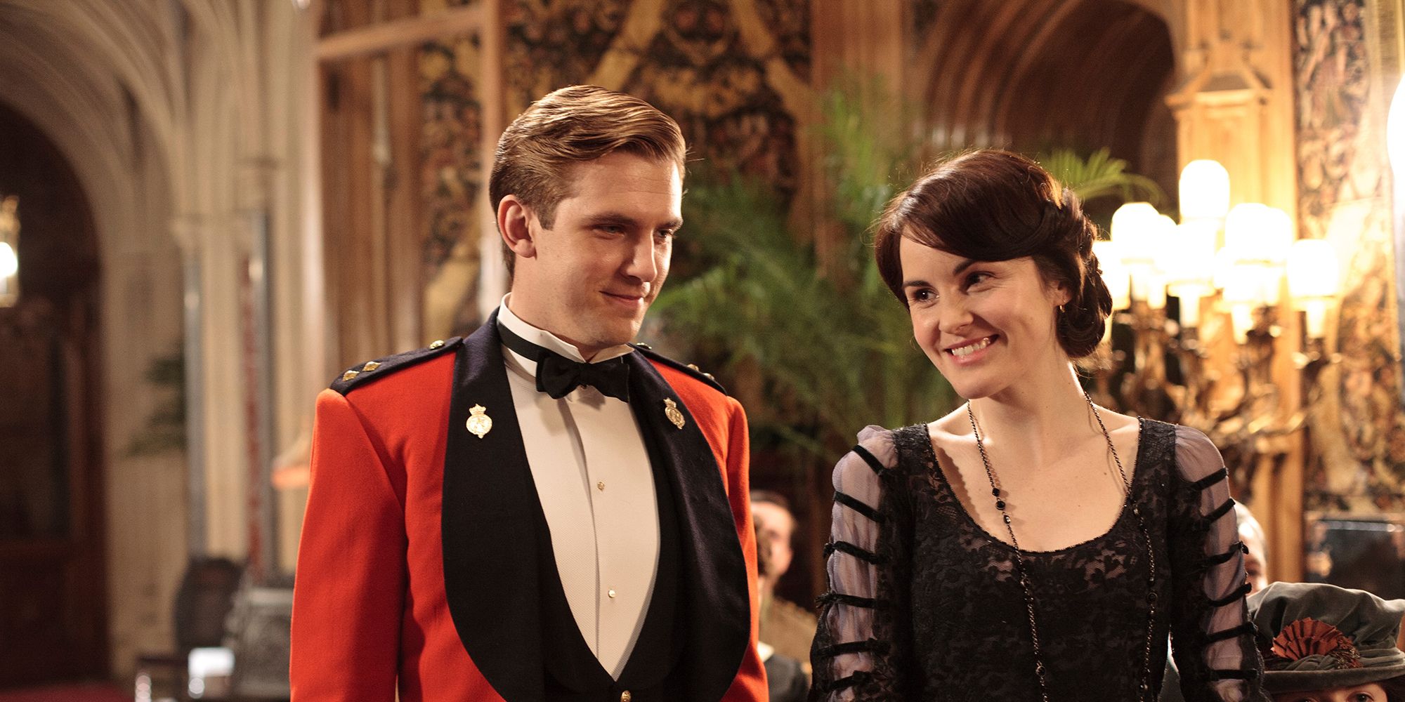 Mary laughs while Matthew smiles in a living room in Downton Abbey.