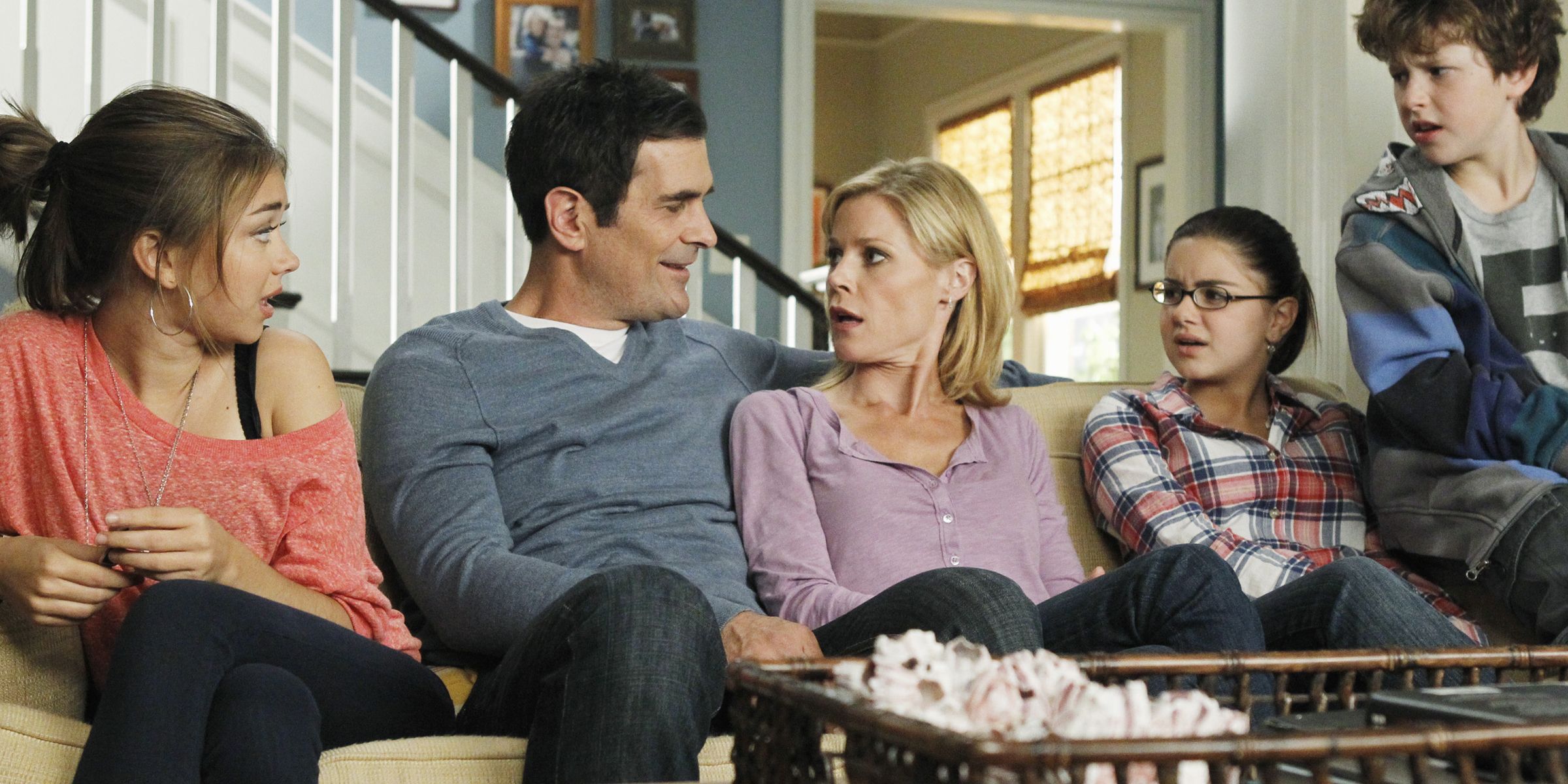 Haley, Phil, Claire, Alex e Luke sentados no sofá juntos em Modern Family