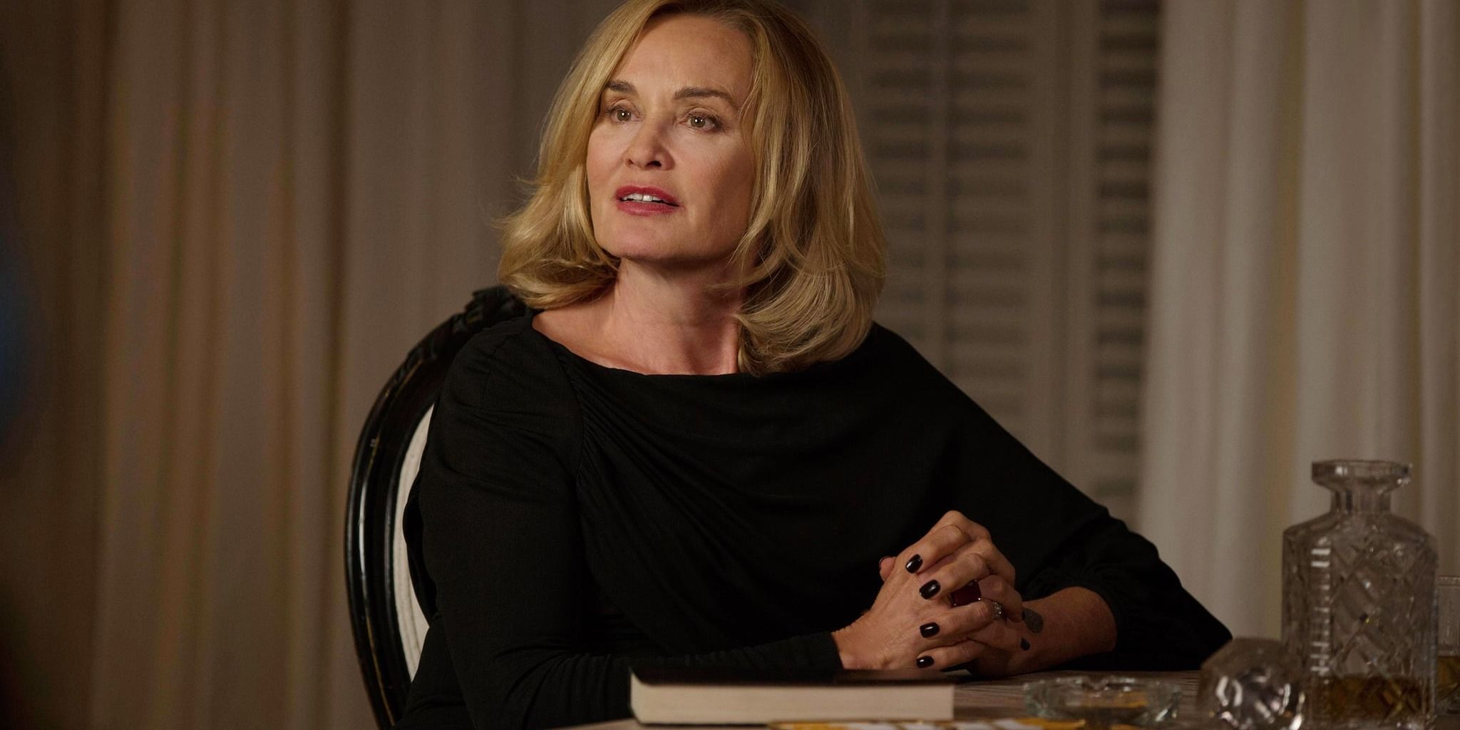 Fiona Goode sitting at a table smiling in American Horror Story Coven