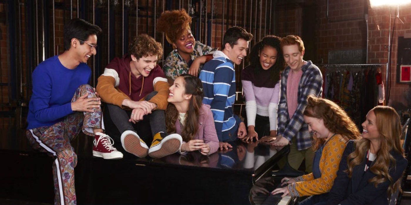 The cast of High School Musical: The Musical: The Series sit on and around the piano