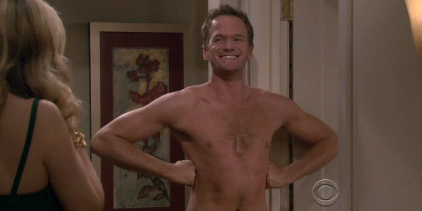 Barney standing shirtless at his door, hands on hips smiling in How I Met Your Mother.