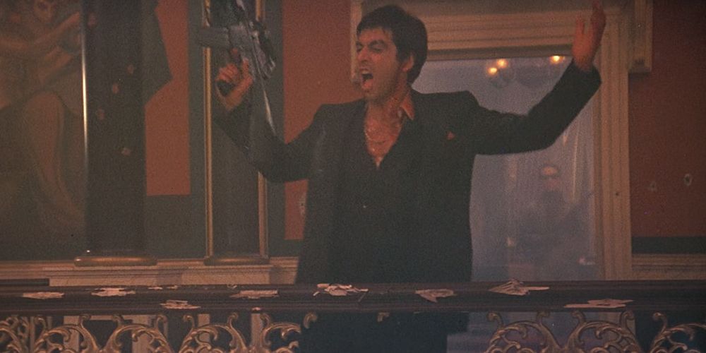 Tony Montana standing on a balcony with a gun and yelling in Scarface.