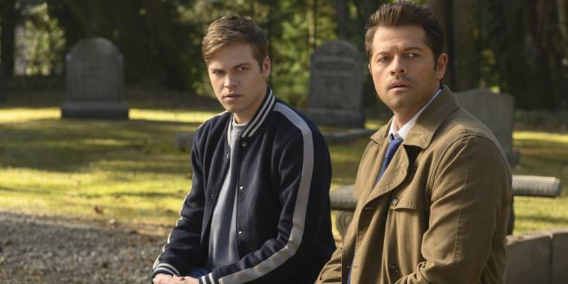 Castiel (Misha Collins) sits on a bench with Jack (Alexander Calvert) in Supernatural