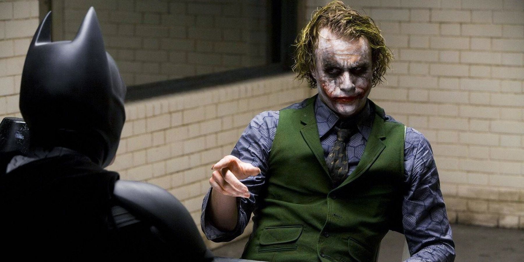 The Joker points at Batman in an interrogation room in The Dark Knight.