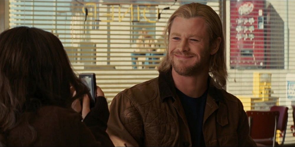Thor smiles while Darcy takes his picture in a diner in his first MCU movie