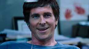 Christian Bale as Michael Burry smiling in his office in The Big Short