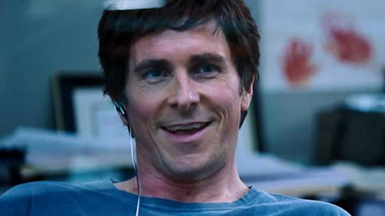 Christian Bale as Michael Burry smiling in his office in The Big Short