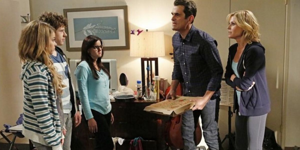 The Dunphys are standing inside a hotel room on Modern Family