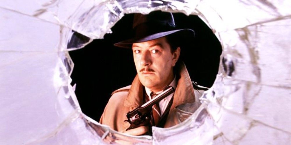 Michael Gambon in a hat and trenchcoat holding a gun in The Singing Detective