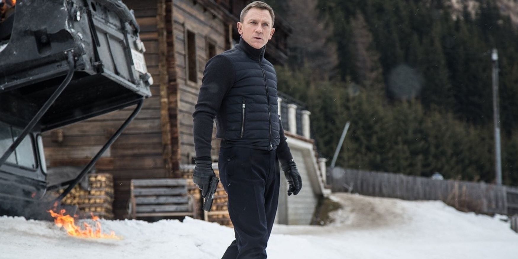 James Bond standing in the snow, holding a gun in Spectre