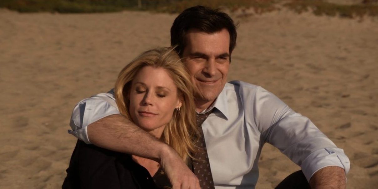 Claire and Phil sitting on a beach in Modern Family