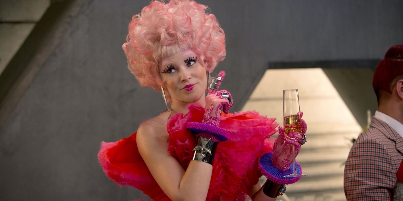 Effie Trinket holding a glass and smiling in The Hunger Games
