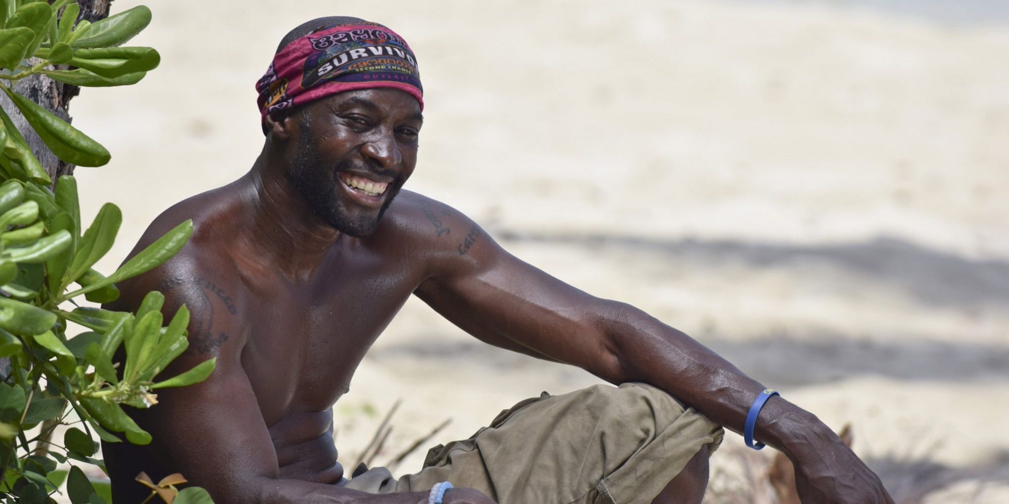 Jeremy Collins from Survivor, sitting on the island, smiling.