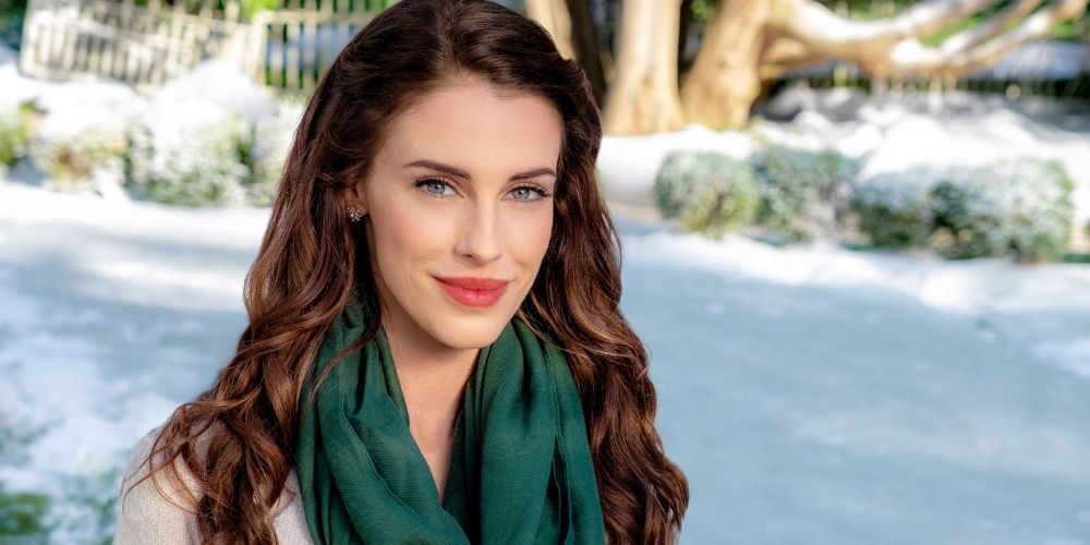 Jessica Lowndes sorrindo em frente a um cenário de neve para Hallmark Christmas Movies