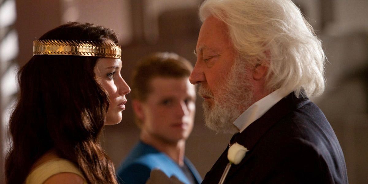 Katniss and President Snow staring at each other while Peeta looks on in The Hunger Games.