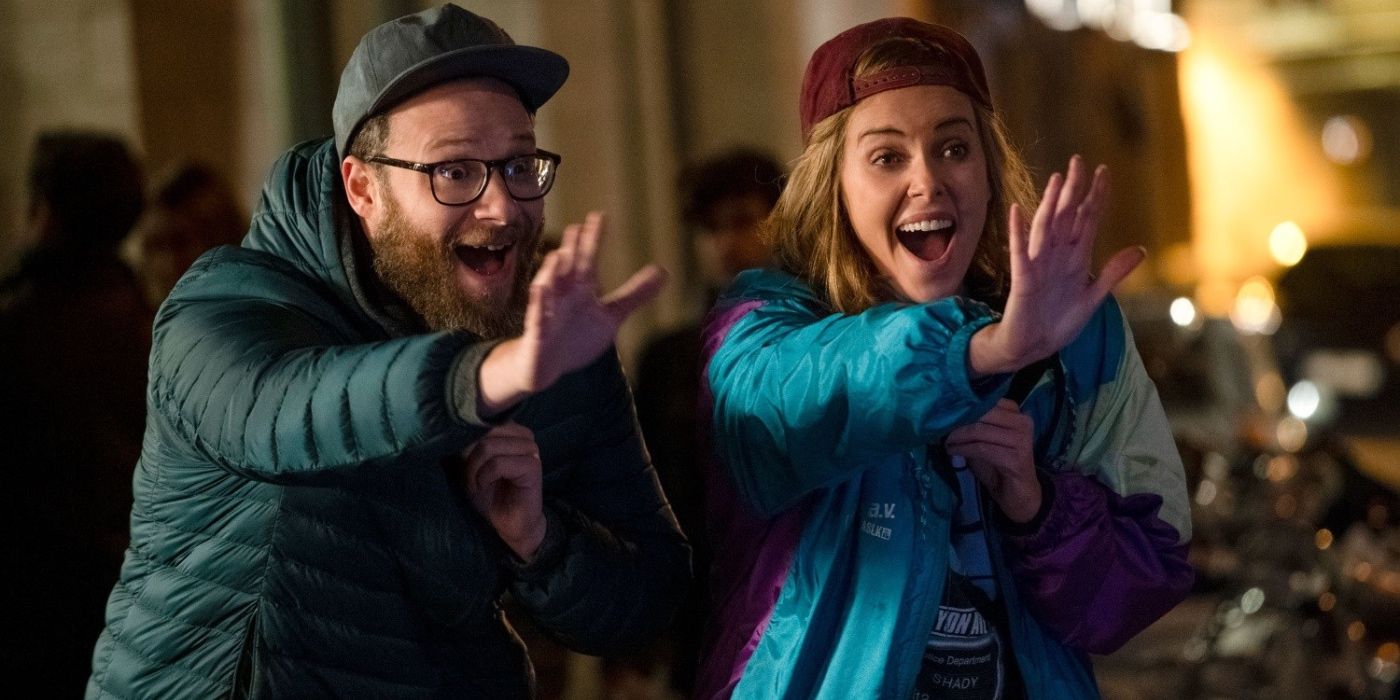 Seth Rogen and Charlize Theron waving excitedly in The Long Shot