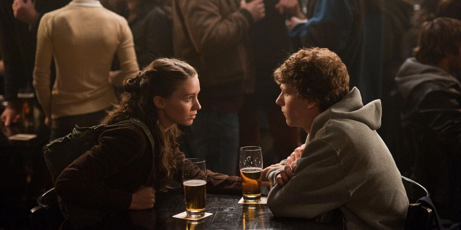 Rooney Mara and Jesse Eisenberg facing each other on a table in The Social Network