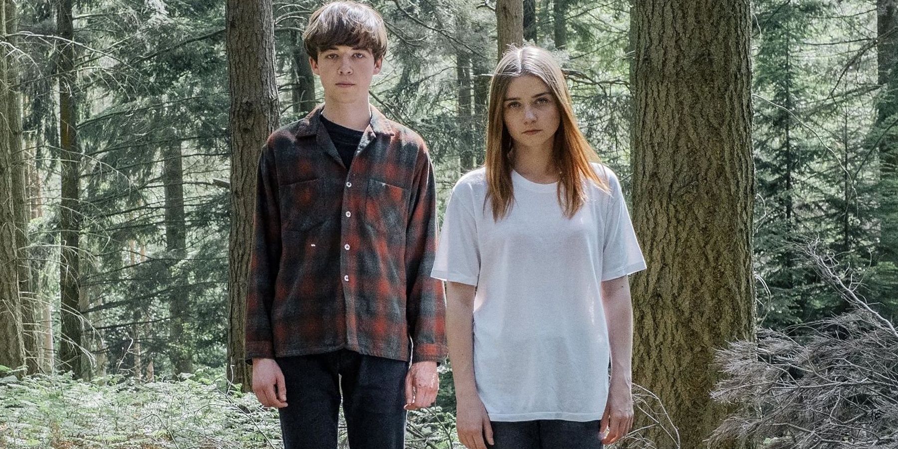 A teenage boy and girl stand in the middle of the woods staring directly at the camera in The End of the Fing World