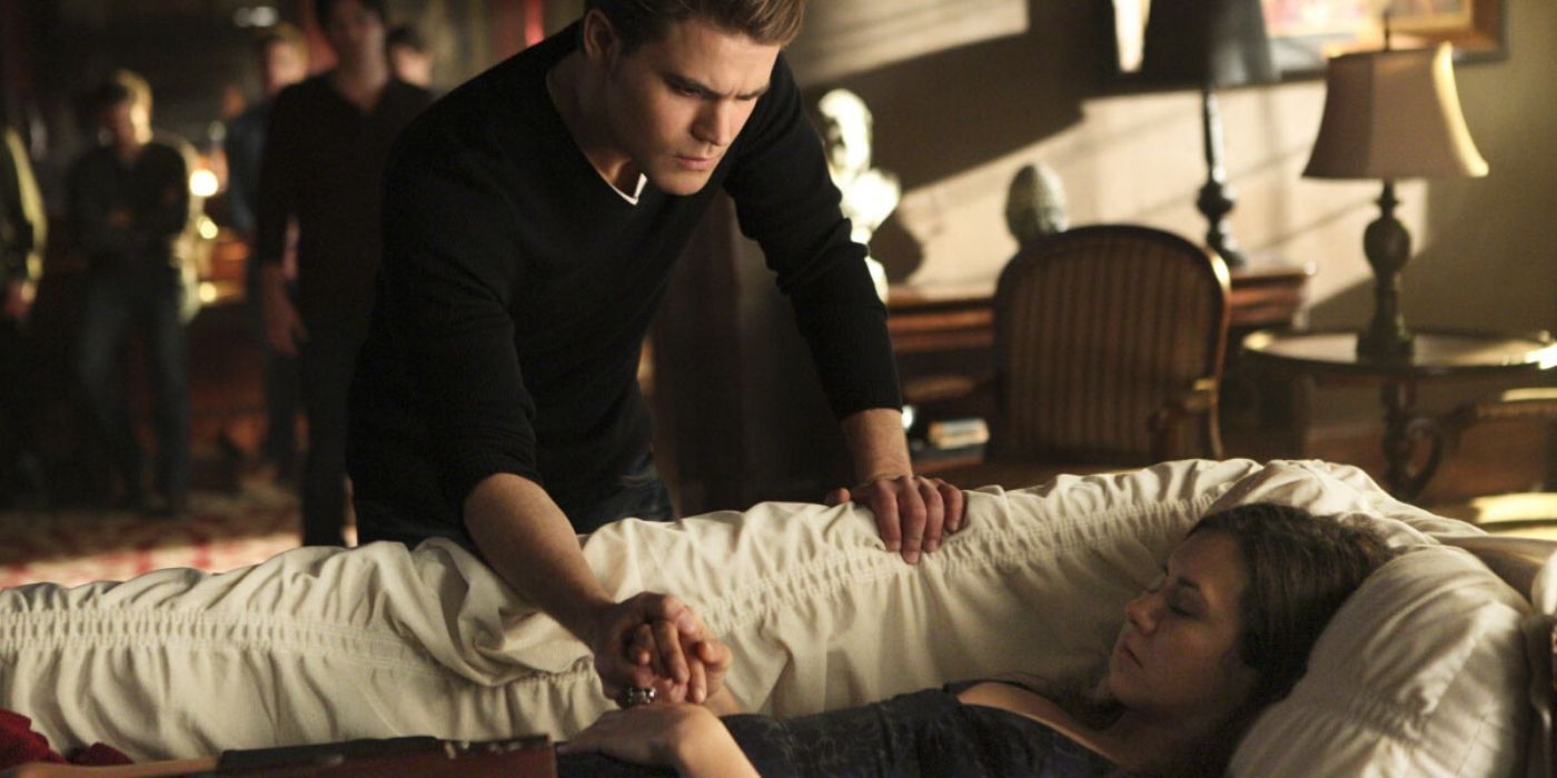 Stefan segura a mão de Elena em seu caixão em The Vampire Diaries.