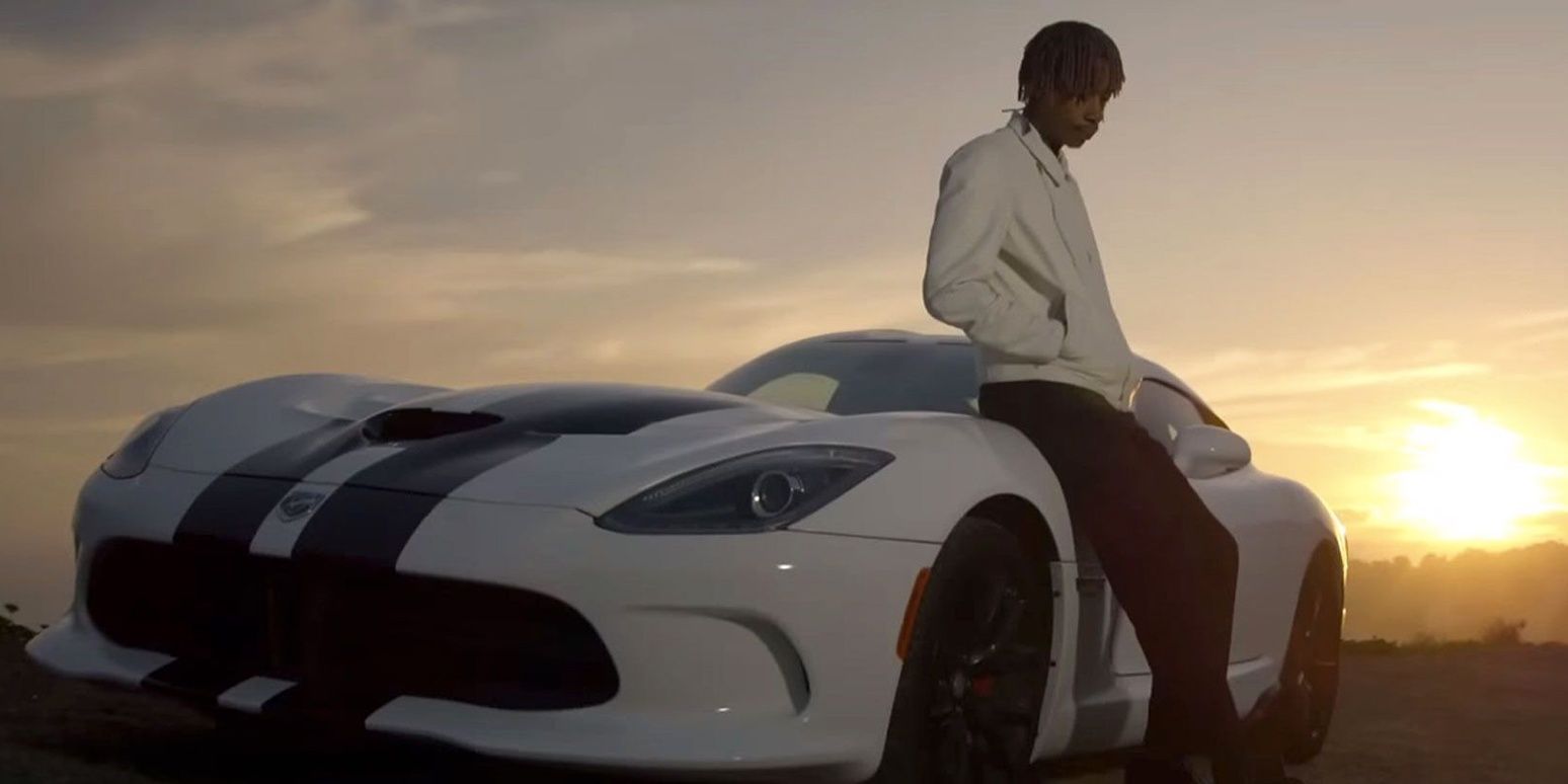 Wiz Khalifa posing next to a car while the sun sets, a still from See You Again's music video