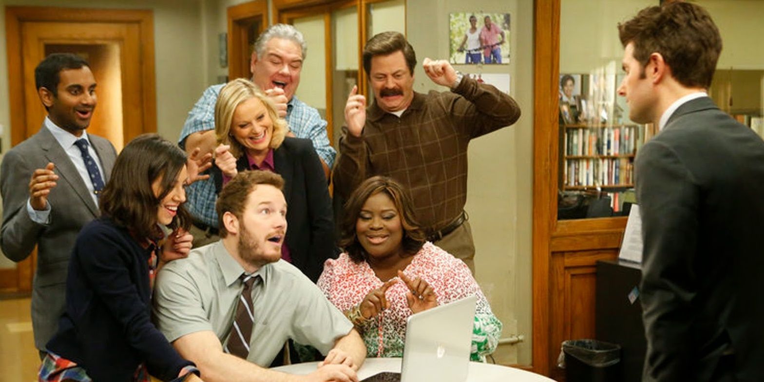 The Parks & Recreation cast laughing around a laptop