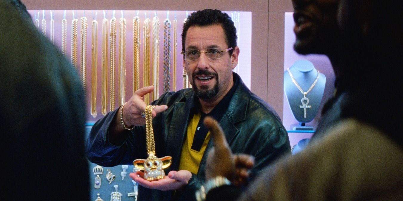 Howard holding up a golden necklace in front of people in Uncut Gems.