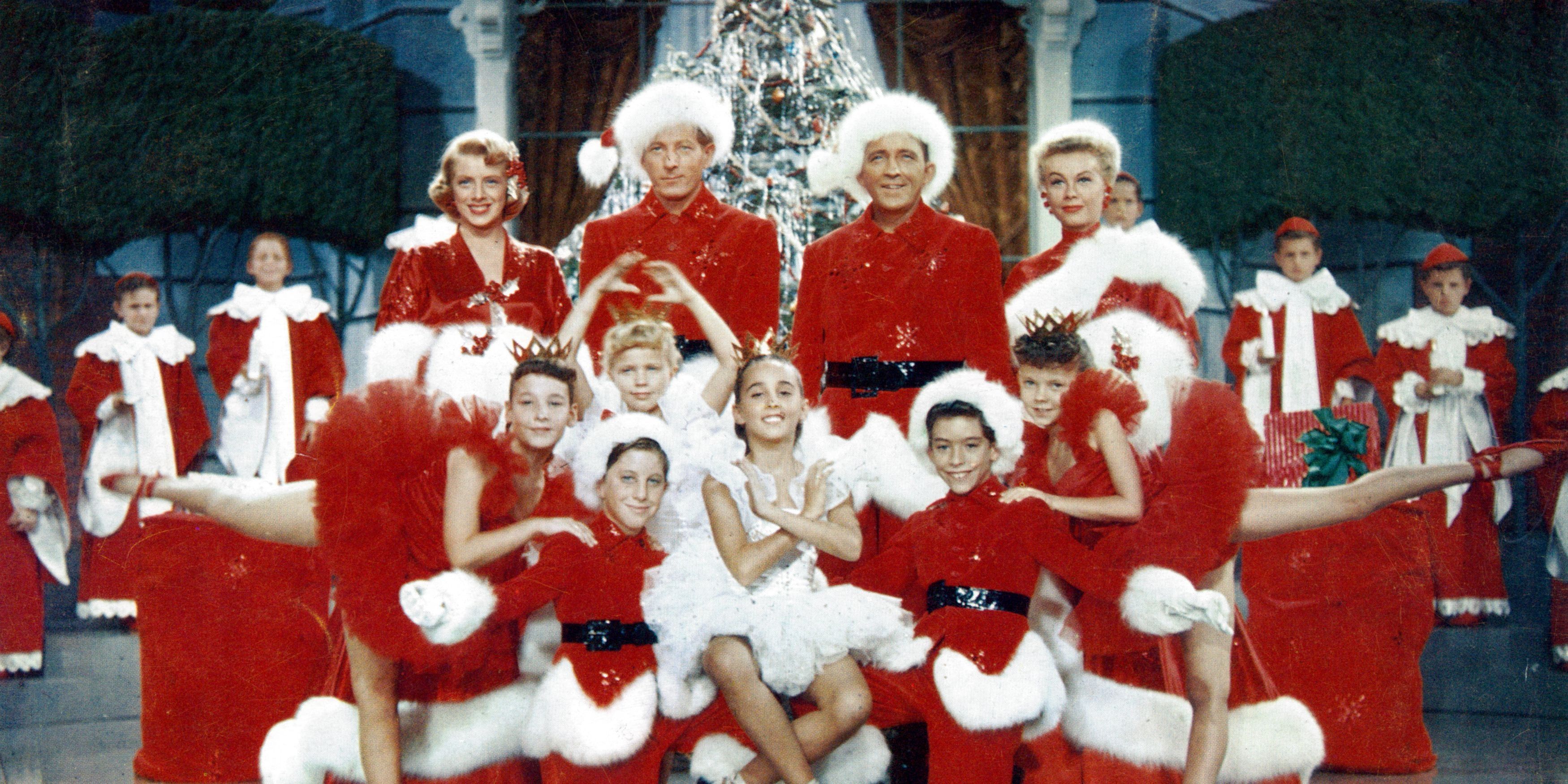 The cast of the musical within White Christmas posing as they sing in red and white outfits