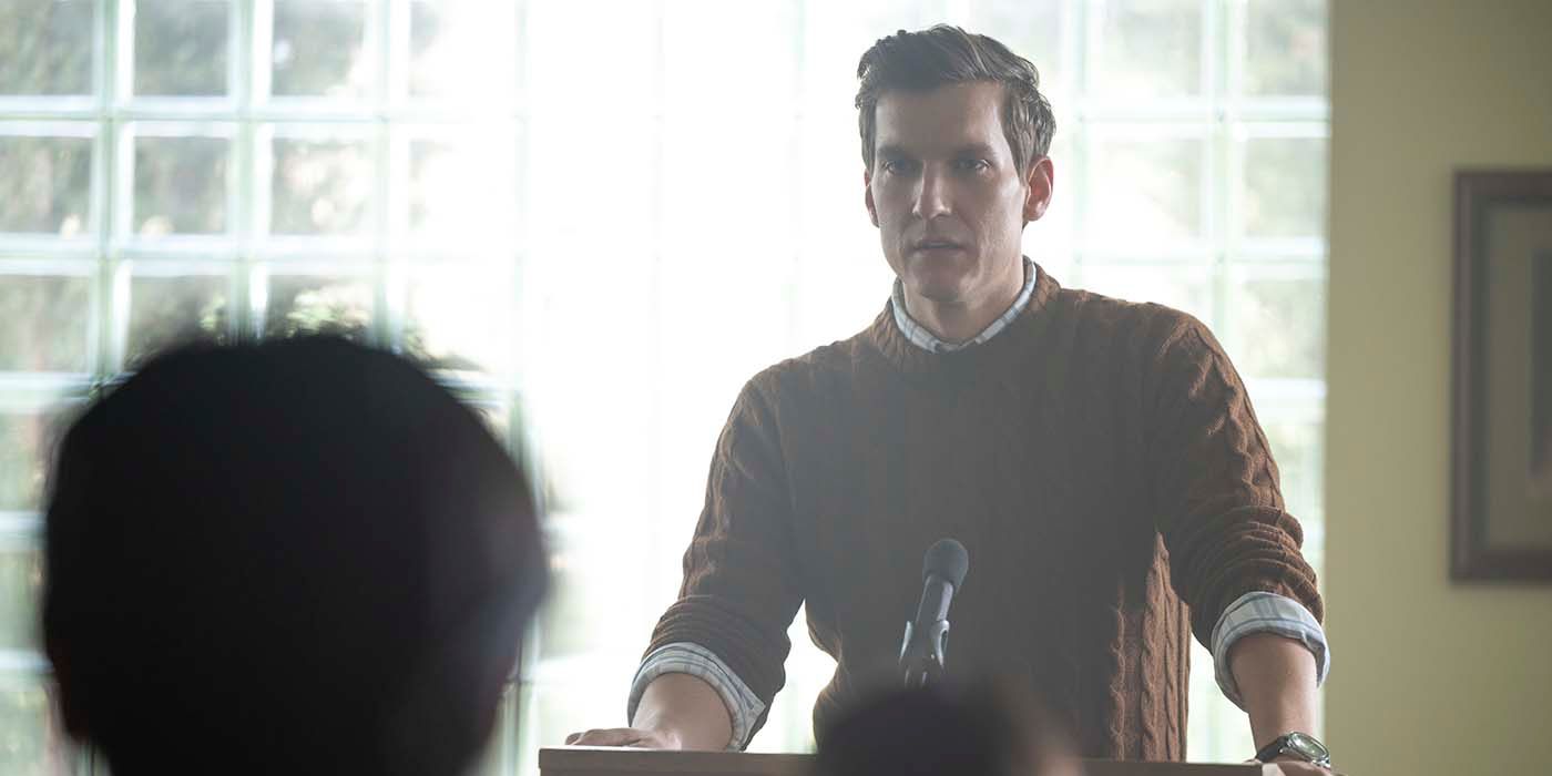 Ryan standing at a podium talking in the second season of Netflix's YOU.
