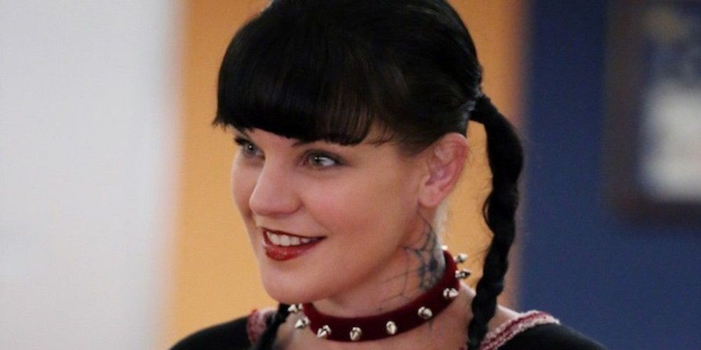 Abby Sciuto from NCIS, smiling wearing a choker and pigtails.