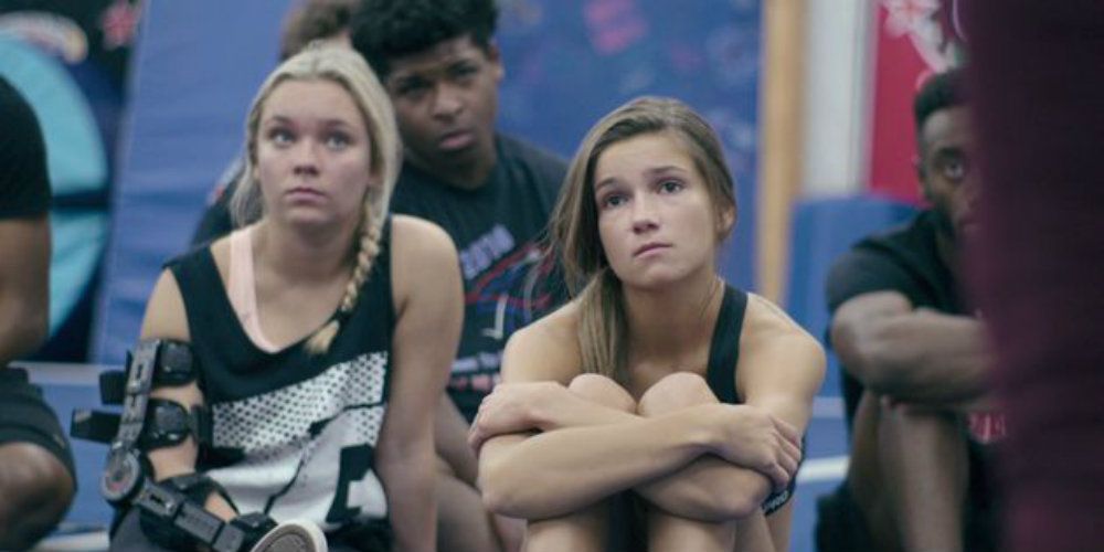 Morgan and a teammate sitting in the gym on Cheer