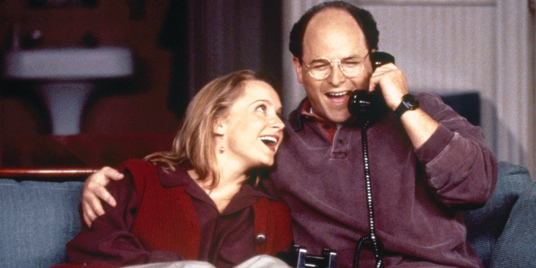 On a couch, George talks on a phone while Susan smiles in Seinfeld.