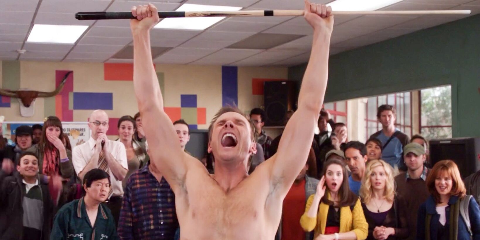 Jeff Winger shirtless raising a pool cue and cheering in celebration in front of a crowd in community