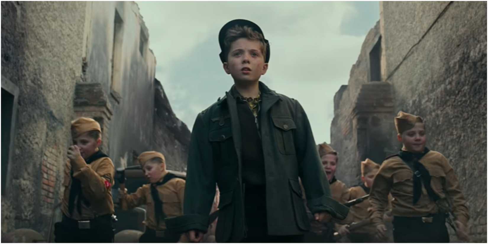 Roman Griffin Davis leads children through the streets in Jojo Rabbit