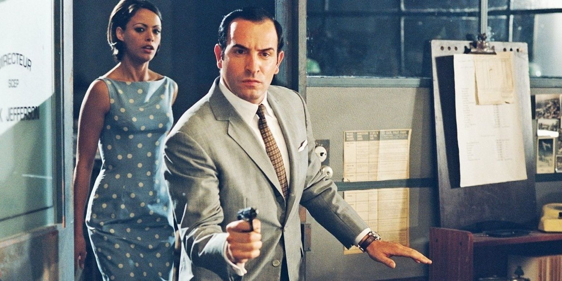 OSS 117 pointing his gun with a lady behind him