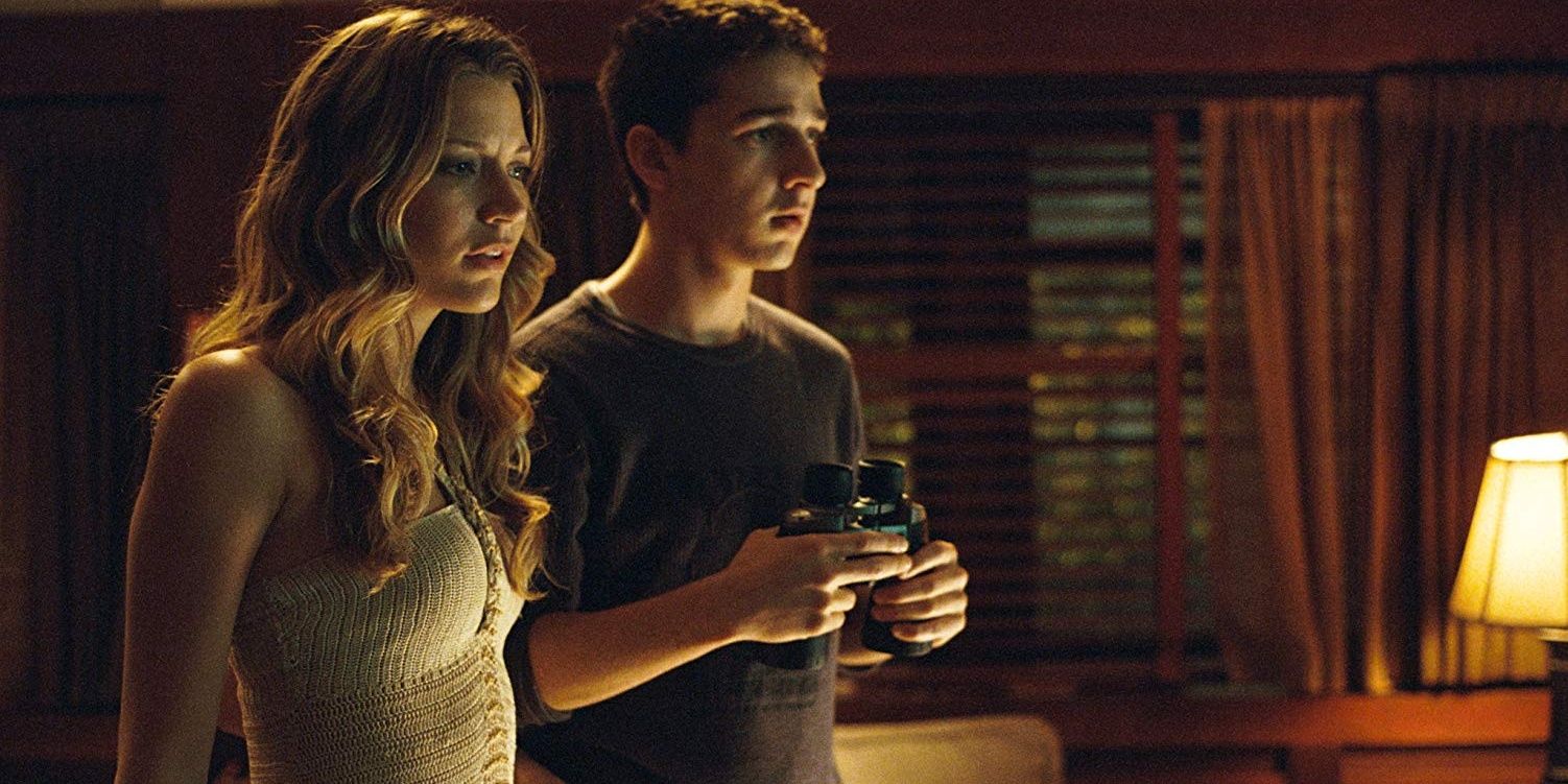Shia LaBeouf and Sarah Roemer staring out a window with binoculars in Disturbia (2007)