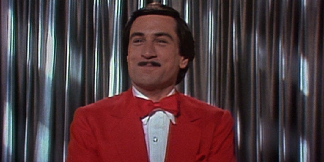 Rupert Pupkin smiling while wearing a red suit in The King Of Comedy.