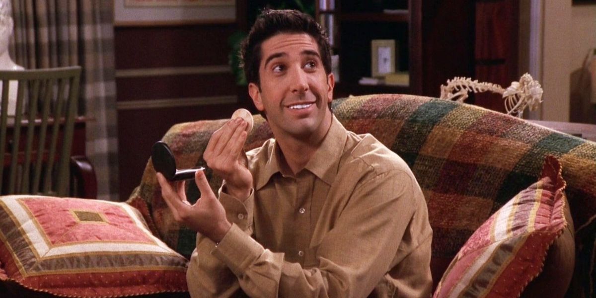 Ross smiling while applying makeup in Friends.