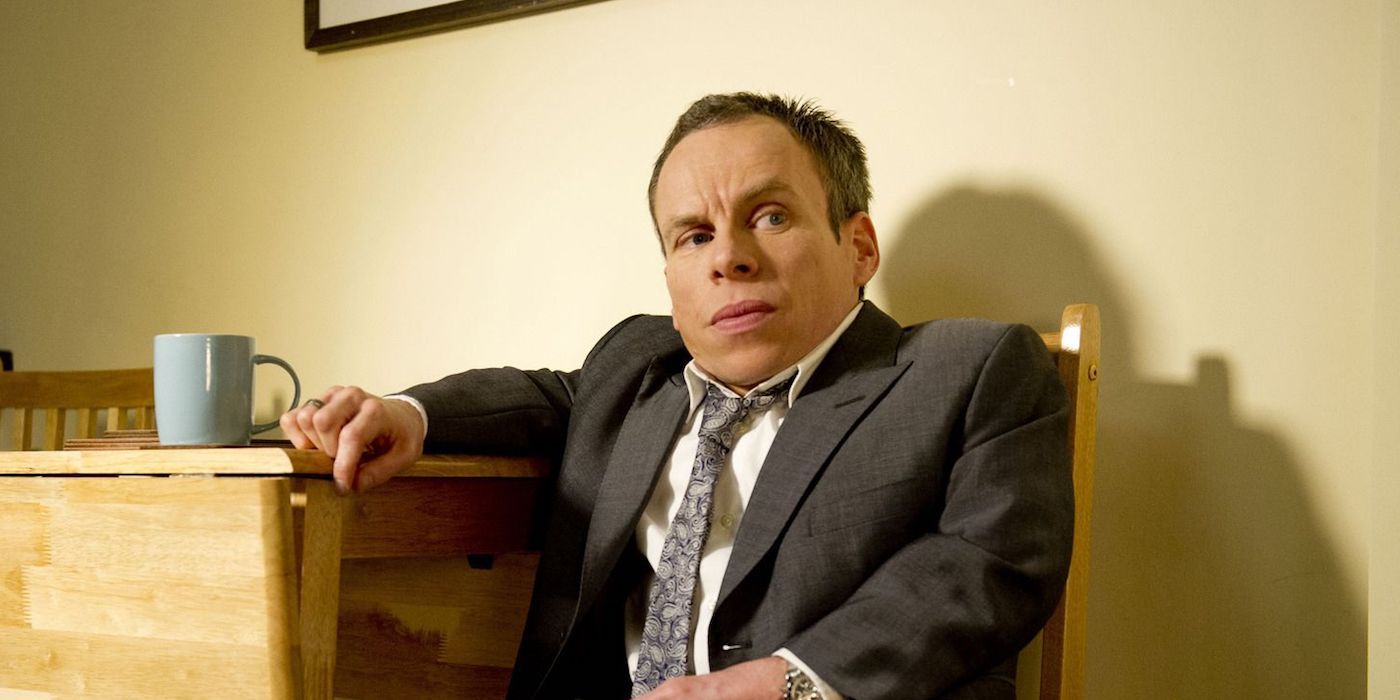 Warwick Davis sitting and looking serious in Lifes Too Short
