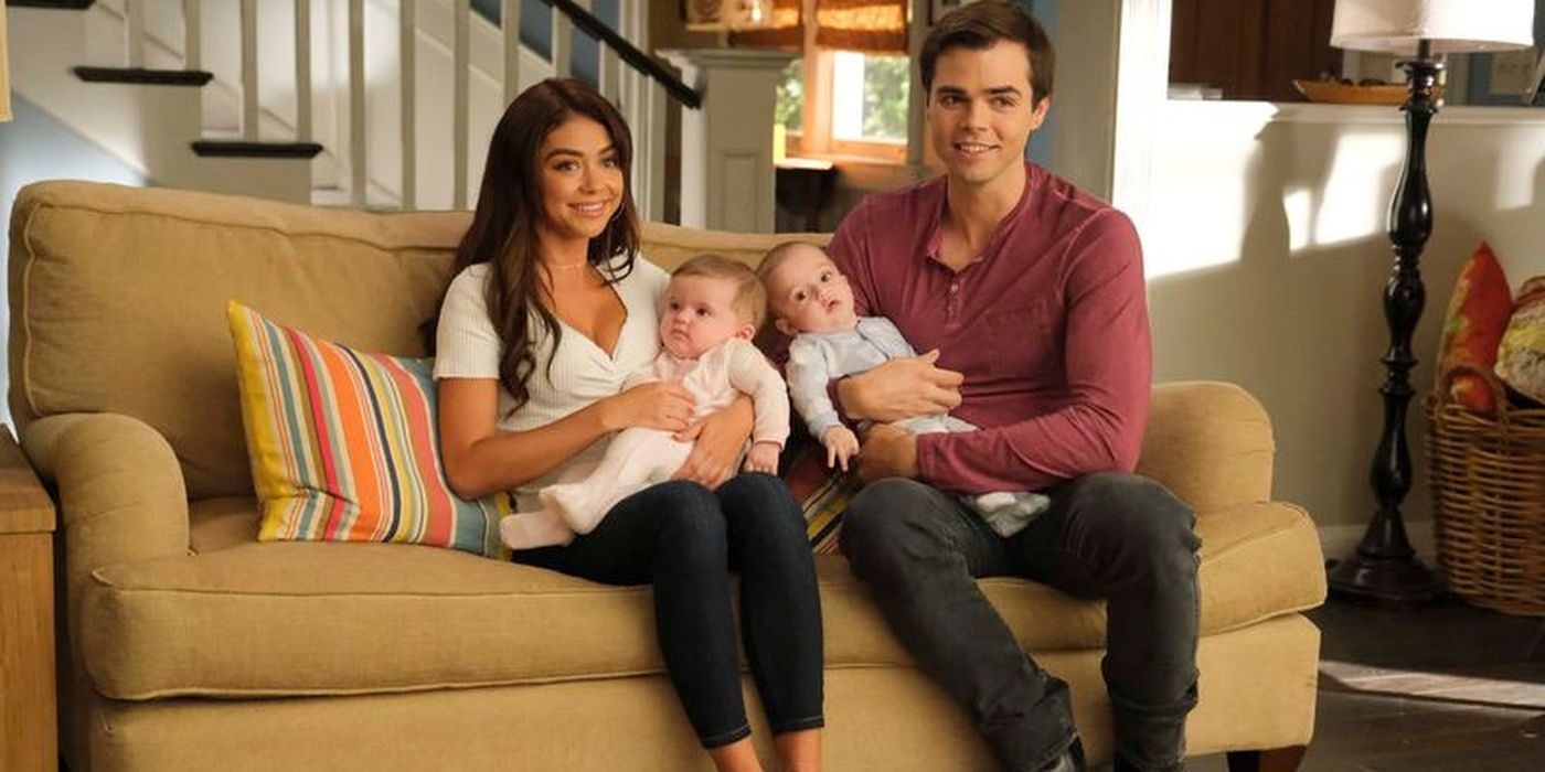Haley and Dylan sitting on the couch with their twins on Modern Family