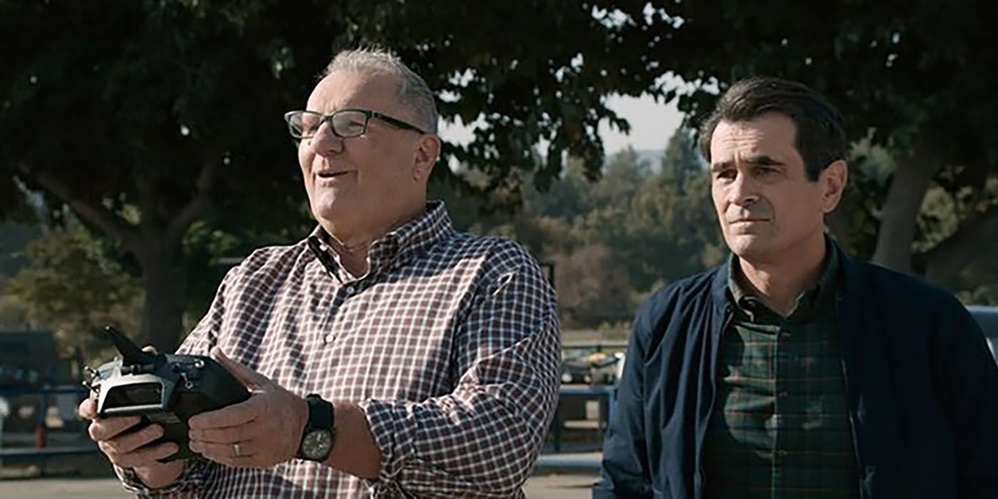 Jay and Phil outside flying a remote-controlled plane on Modern Family
