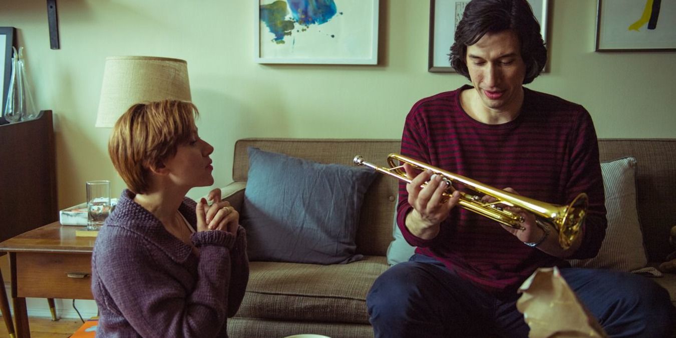 Adam driver holds a trumpet in Marriage Story as Scarlet Johansson looks on