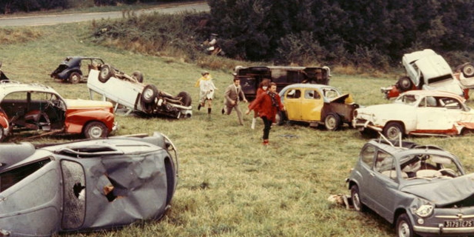 A group of children running through a field with broken cars in Week-End.
