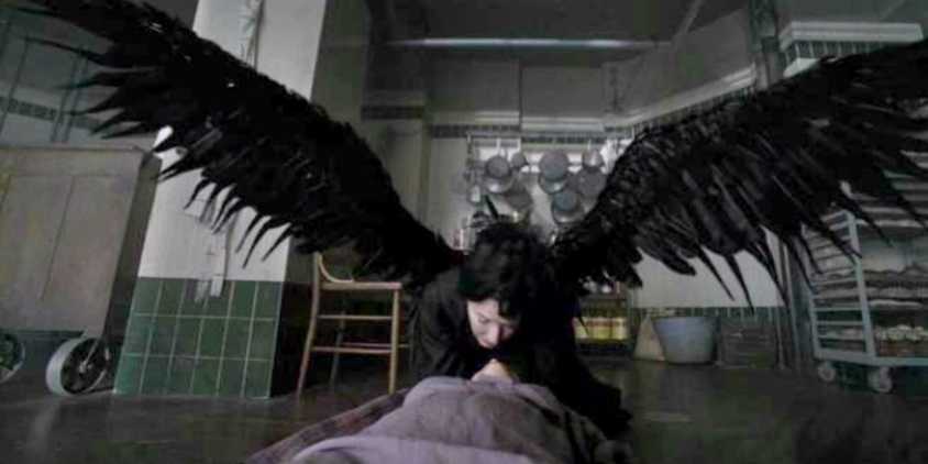 Shachath leans over someone while spreading her wings in American Horror Story: Asylum