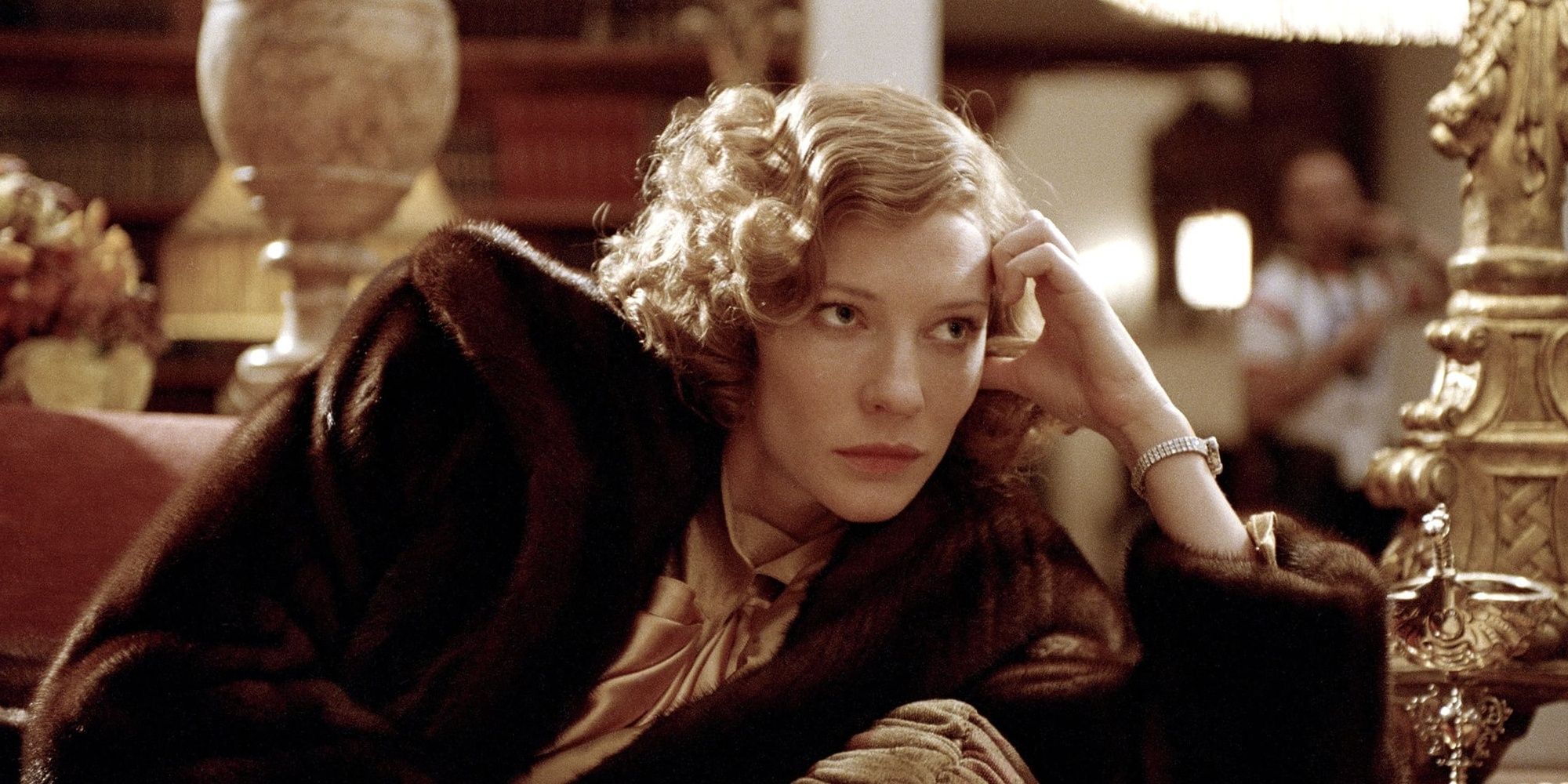 Cate Blanchett como Katharine Hepburn apoiando a cabeça na mão e parecendo preocupada em O Aviador.