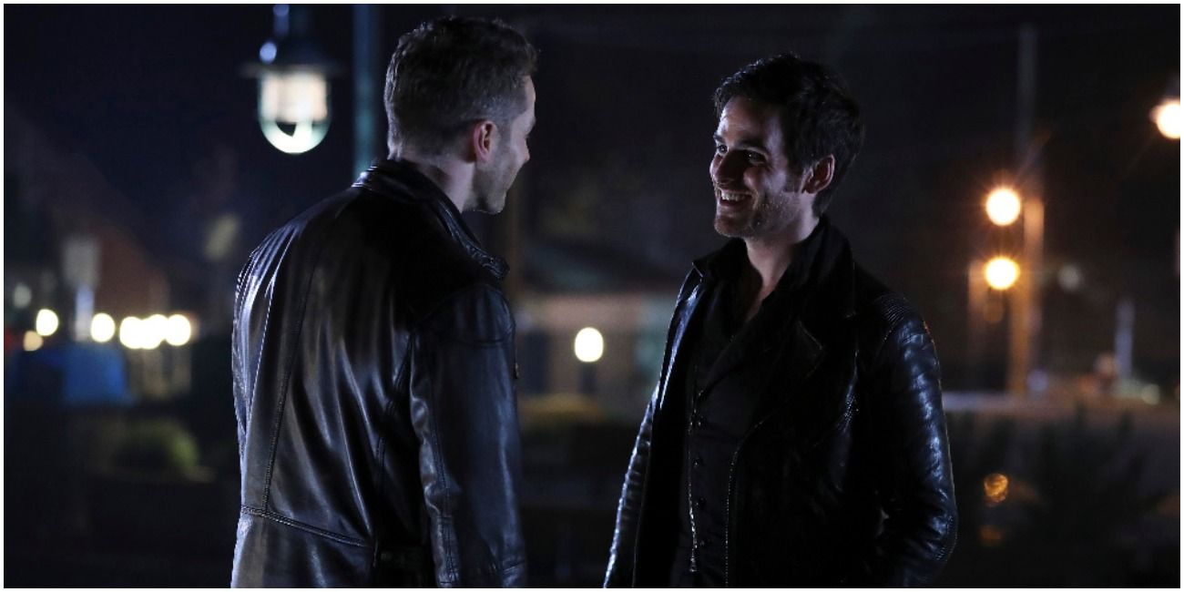 Charming and Hook in Once Upon a Time standing outside in the dark, laughing together.