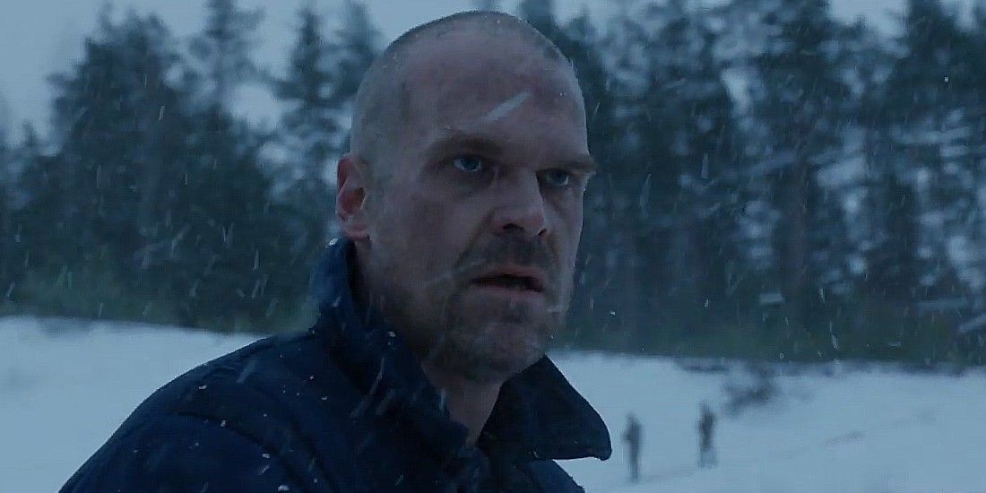 David Harbour as Hopper walking through a snowy woods in Stranger Things season 4