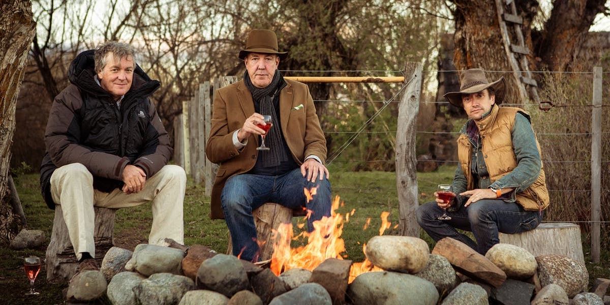 James May, Jeremy Clarkson, and Richard Hammond sitting around a fire with drinks and looking at the camera in the Top Gear Patagonia Special