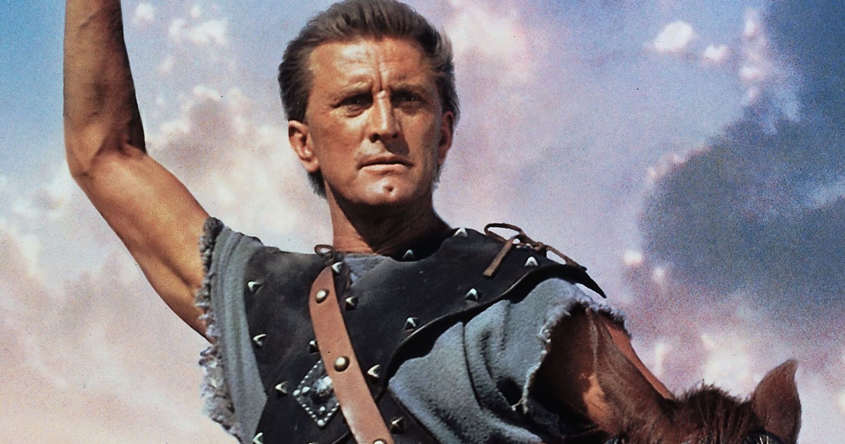 Kirk Douglas raising his arm and riding a horse in Spartacus